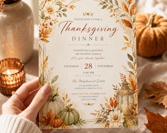 May include: A Thanksgiving dinner invitation card featuring a cream background with a watercolor border of autumn leaves, berries, white flowers, pumpkins, and a lantern. The text reads: Please join us for a Thanksgiving dinner, Thursday 28 November.