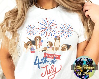 Op de afbeelding: Wit T-shirt met een afbeelding van vier beagle-honden die een zonnebril dragen en de 4e juli vieren met vuurwerk en een cupcake. De tekst "Happy 4th of July" staat op het shirt gedrukt.