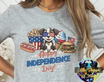 May include: Gray t-shirt with a cartoon dog wearing sunglasses and a red, white, and blue bandana. The dog is surrounded by various American-themed food items, including popcorn, hot dogs, ice cream, and a hamburger. The text "Happy Independence Day!" is printed below the dog.