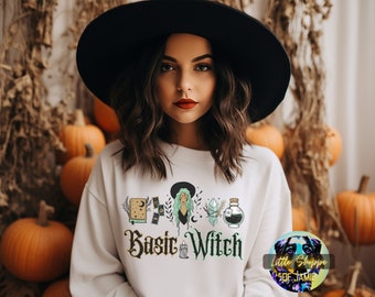 May include: White sweatshirt with the text "Basic Witch" in black and green lettering. The design includes a witch with green hair, a book, a crystal, a potion bottle, and a crescent moon.