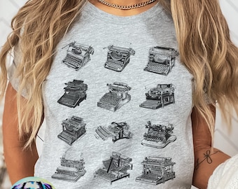 May include: Gray t-shirt with a vintage typewriter design. The shirt features 12 different typewriter illustrations in black and white.