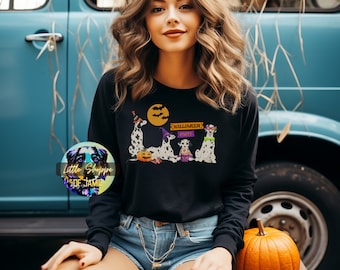 May include: A black long-sleeved sweatshirt with a graphic of three Dalmatian dogs dressed in Halloween costumes. The dogs are wearing hats, a witch's hat, and sunglasses. The text "Halloween Party" is above the dogs.
