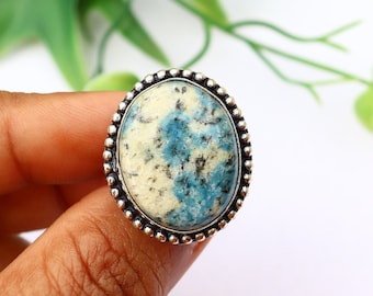 May include: Oval-shaped blue and white kyanite gemstone ring set in a silver bezel with a beaded edge.