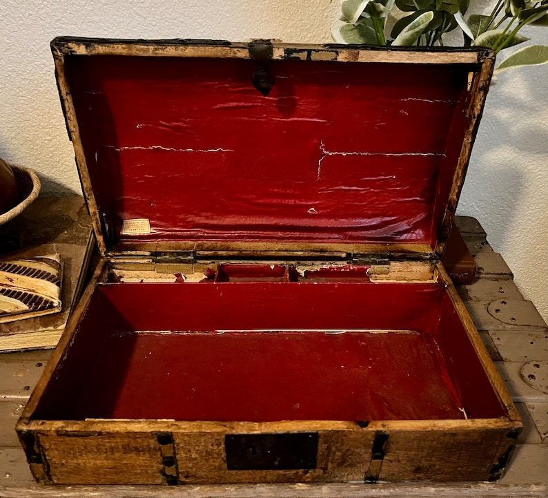 May include: An antique wooden box with a red velvet lining and a brass latch. The box has a compartment with multiple sections.