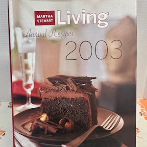 May include: A white ceramic mug with a black handle and the text "But First, Coffee" in a black, bold font. The mug is on a white surface.