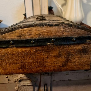 May include: A wooden box with a dark brown stain and black metal trim. The box has a curved top and is decorated with metal studs.