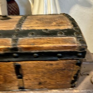 May include: A wooden chest with black metal accents and rivets. The chest has a hinged lid and is made of dark wood.