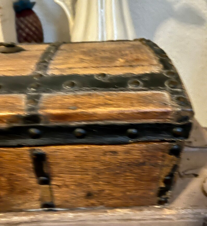 May include: A wooden chest with black metal accents and rivets. The chest has a hinged lid and is made of dark wood.