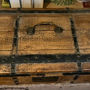 May include: A wooden chest with a metal latch and handle. The chest is decorated with metal bands and studs.