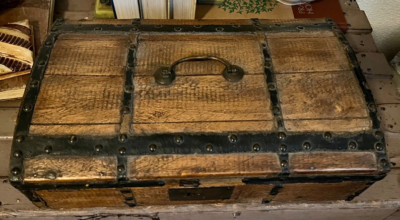 May include: A wooden chest with a metal latch and handle. The chest is decorated with metal bands and studs.
