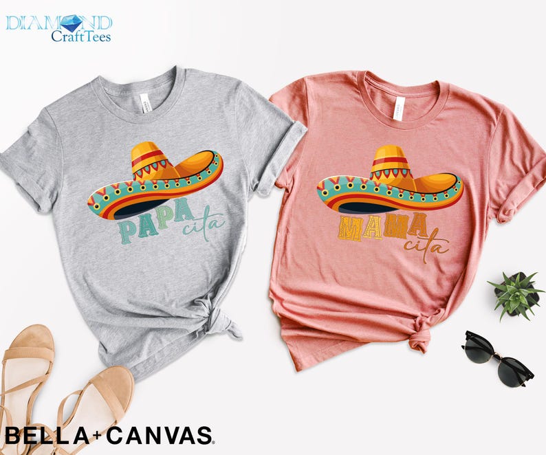 Puede incluir: Dos camisetas grises y rosas con un dise&ntilde;o de sombrero colorido y el texto "Papa cita" y "Mama cita" impreso en ellas.