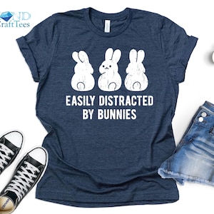 May include: A navy blue t-shirt with a distressed white graphic of three bunnies and the text "Easily Distracted By Bunnies".