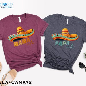 Puede incluir: Dos camisetas con un dise&ntilde;o de sombrero colorido y texto. La camiseta granate dice "Mamacita" y la camiseta azul dice "Papa cita".