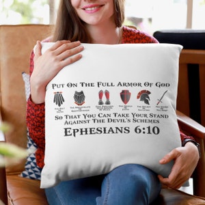 Puede incluir: Coj&iacute;n blanco con un gr&aacute;fico negro y rojo de la armadura de Dios. El texto dice "Ponte la armadura completa de Dios" y "Efesios 6:10".