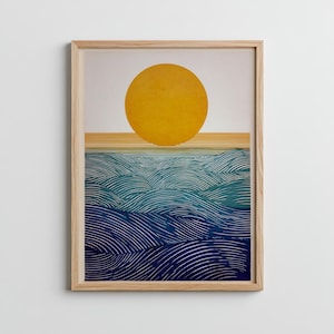 May include: A framed art print featuring a minimalist landscape. A large yellow sun sits above a horizon line, with stylized blue and teal waves below. The artwork is in a natural wood frame.