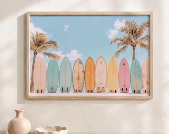 May include: A framed wall art print featuring a row of nine colorful surfboards standing upright on a sandy beach. The surfboards are in shades of cream, teal, blue, tan, orange, yellow, and pink, set against a clear blue sky with palm trees.
