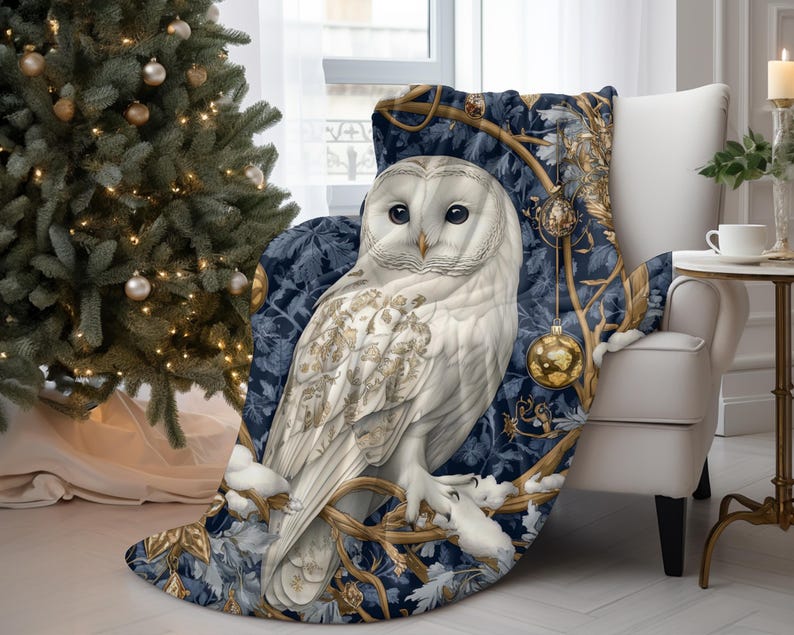 May include: A white owl with gold accents sits on a branch with blue and gold leaves. The owl is surrounded by gold ornaments and a blue background. The owl is a throw blanket.