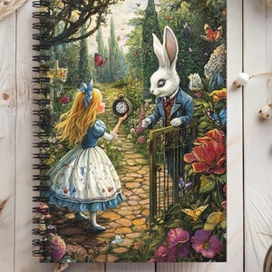 Op de afbeelding: Een spiraalgebonden notitieboek met een kleurrijke illustratie van Alice in Wonderland. Alice houdt een zakhorloge vast en een wit konijn met een vest staat bij een poort.
