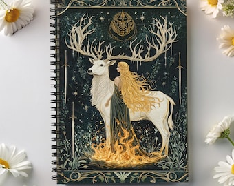Puede incluir: Una libreta de espiral con una cubierta verde oscuro que presenta un ciervo blanco con grandes cuernos y una mujer con el pelo largo y rubio de pie a su lado. El ciervo y la mujer están rodeados por un fuego dorado y un bosque verde oscuro. La cubierta también presenta un patrón de estrellas doradas y un círculo dorado con un símbolo en el centro.