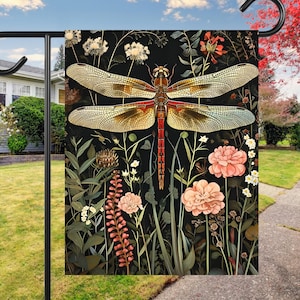 May include: A garden flag with a black background featuring a large dragonfly with red and yellow wings, surrounded by pink flowers and green foliage.