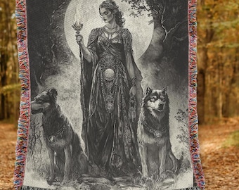 May include: A black and white woven tapestry featuring a woman in a long dress standing in a forest with two wolves. The woman is holding a staff with a flower on top. The moon is shining brightly in the background.