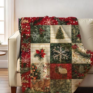 May include: A red, green, and cream colored throw blanket with a patchwork design featuring snowflakes, pine trees, and other wintery motifs.