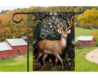 May include: A garden flag depicting a detailed illustration of a white-tailed deer standing in a lush forest setting. The deer has a large rack of antlers and is depicted in a realistic style. The background is a dark green with hints of brown and yellow.