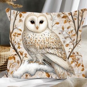 May include: A white owl with brown markings sits on a branch with brown and white flowers. The owl is perched on a snowy branch with a white background. The owl is looking to the left of the image.