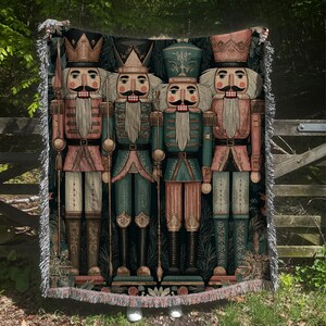 May include: A woven tapestry featuring four toy soldier nutcrackers in shades of pink, teal, and gold. The nutcrackers are depicted in a symmetrical arrangement, each holding a staff or weapon. The background is a dark green with floral patterns.
