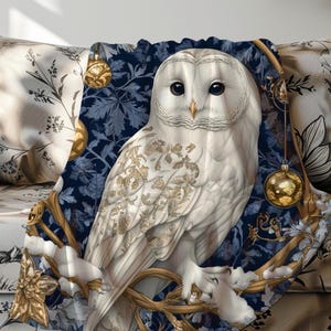 May include: A white owl with gold accents sits on a branch with blue and gold ornaments hanging from it. The owl is surrounded by a blue and gold patterned background.