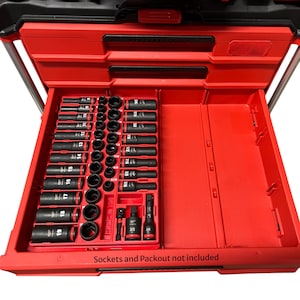 Può includere: Una cassetta degli attrezzi rossa con coperchio e cassetto neri. Il cassetto aperto rivela un set di bussole nere di varie dimensioni, ben disposte in un vassoio rosso. Il testo "Sockets and Packout not included" è visibile in basso.