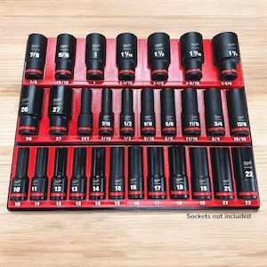 Può includere: Un set di bussole nere con dettagli rossi, organizzate in un vassoio rosso. Le bussole sono etichettate con misure in pollici, che vanno da 7/8 a 1-1/4 pollici (circa 2,2 a 3,2 cm). Il testo "Sockets not included" è visibile.