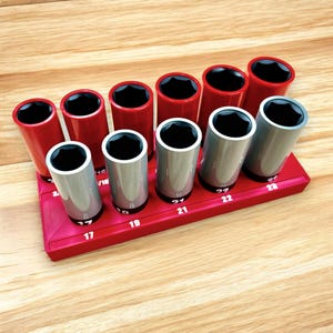May include: A red and silver socket wrench set with 10 sockets ranging in size from 17 to 23 mm. The sockets are organized in a red plastic holder with white numbers indicating the size of each socket.