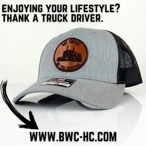 May include: Gray and black trucker hat with a brown leather patch that says "We Drive So You Survive" and a picture of a semi-truck. The hat has a black mesh back.
