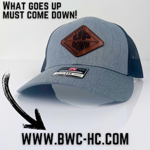 May include: A gray and black trucker hat with a brown leather patch that says "What Goes Up Must Come Down" and a logo that says "Up Down".
