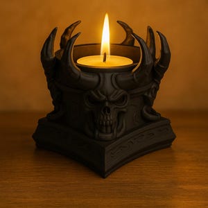 May include: Black candle holder with a skull design and curved horns. The candle holder has a lit, round candle in the center. The candle holder is on a wooden surface.