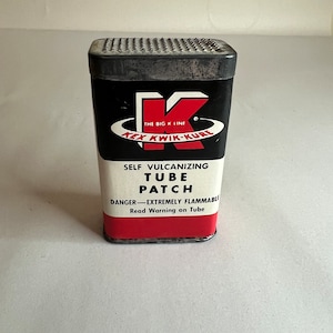 Könnte beinhalten: Ein roter und schwarzer Metallbehälter für Schlauchpflaster mit dem Text "THE BIG K LINE KEX KWIK-KURE SELF VULCANIZING TUBE PATCH DANGER-EXTREMELY FLAMMABLE Read Warning on Tube".