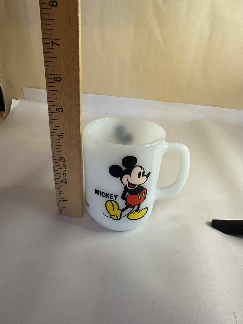 Pu&ograve; includere: Una tazza bianca e piccola con Topolino. La tazza ha un manico e una grafica colorata di Topolino. La tazza &egrave; alta circa 7,6 cm.
