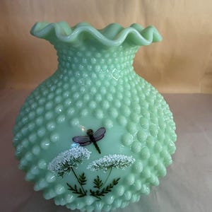 Op de afbeelding: Een lichtgroene hobnail glazen lampenkap met een gerimpelde rand. De kap heeft een geschilderd ontwerp van een paarse libelle en witte bloemen met groene stelen en bladeren.