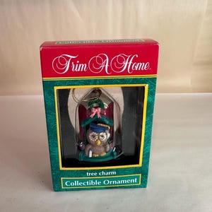 May include: A green and red box with a clear plastic window showing a small owl wearing a graduation cap and holding a scroll. The box says "Trim A Home" and "tree charm collectible ornament".