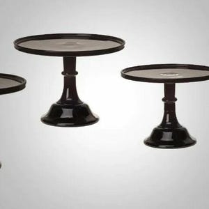 May include: Set of four black cake stands of varying sizes. The stands are made of glass and have a smooth, polished finish.