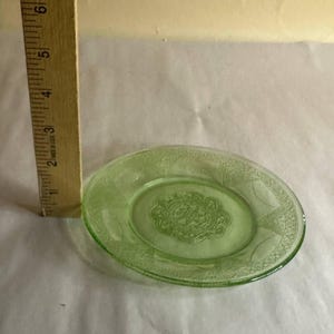 Può includere: Un piatto di vetro verde con un motivo floreale. Il piatto ha un diametro di circa 15 cm.