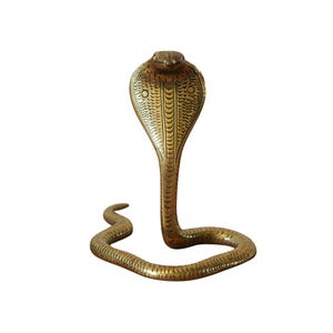 May include: A detailed brass cobra statue with a flared hood and a curved body. The snake is a golden-brown colour and stands upright, with intricate scale detailing. The statue is a decorative item.
