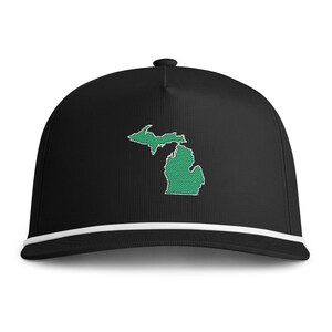 Puede incluir: Una gorra de béisbol negra con un mapa bordado en verde del estado de Michigan, con un contorno blanco y centrado en el panel frontal. La gorra incluye un detalle de cordón blanco que recorre horizontalmente la base de la corona sobre la visera.