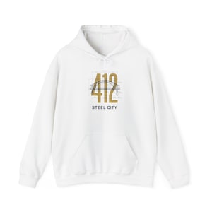 May include: A white long-sleeve hooded sweatshirt featuring a central graphic with the large gold numbers 412, a black line drawing of a bridge, technical blueprint-style grid lines, and the black text STEEL CITY printed underneath the design.