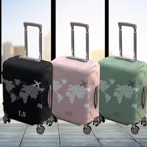 Könnte beinhalten: Drei Koffer mit personalisierten Initialen, "LS", "SP" und "AC", zeigen ein Weltkarten-Design mit einem Herzen und Flugzeugen. Die Koffer sind schwarz, rosa und grün.