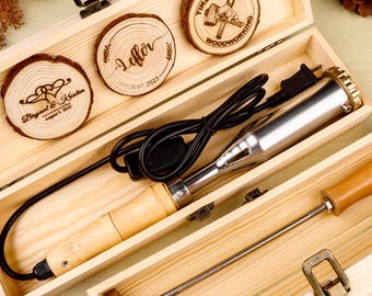 May include: A wooden box with a wood-burning tool and three engraved wooden coasters. The coasters have personalized text and designs. The wood-burning tool has a wooden handle and a metal tip. The box is made of light-colored wood.