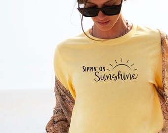 May include: A yellow long-sleeve t-shirt with the text "Sippin' on Sunshine" and a stylized sun graphic.