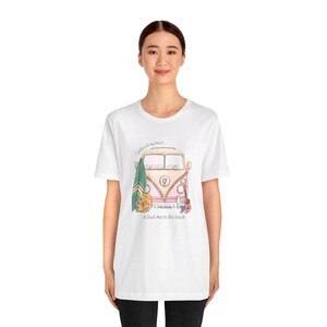 May include: White t-shirt with a pink and yellow vintage van illustration. The van has a surfboard, a guitar, and a suitcase on the side. The text on the shirt reads "I followed my heart, it lead me to the beach."