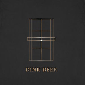Peut inclure: T-shirt noir avec un graphique doré représentant un terrain de pickleball. Le texte "DINK DEEP." est imprimé en dessous. Le t-shirt est en matière douce, idéal pour un usage décontracté.